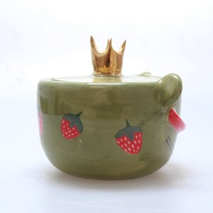 May include: Green ceramic jar with a gold crown lid and strawberry designs.