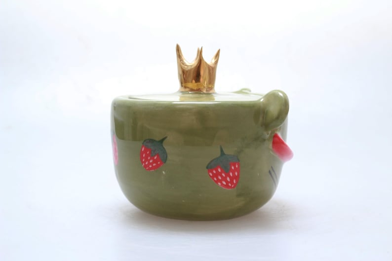 May include: Green ceramic jar with a gold crown lid and strawberry designs.