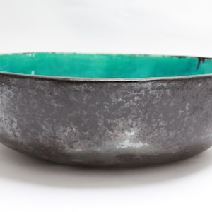 Puede incluir: Un cuenco de cerámica grande, de forma ovalada, con un exterior gris oscuro y un interior turquesa brillante.