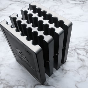 May include: A black metal storage organizer with multiple compartments. The organizer has a label that reads "2.0oz".
