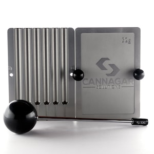 May include: A silver metal mold with six cylindrical cavities for making cannagar sticks. The mold is labeled "CANNAGAR SOLUTIONS" and has a logo of a stylized letter "S". A black metal tamper is included.