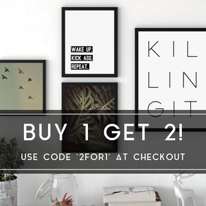 May include: Three framed prints with motivational quotes. The top print says "Wake Up. Kick Ass. Repeat." The middle print says "Killin It." The bottom print is a photo of tropical leaves. The text "BUY 1 GET 2! USE CODE "2FORI" AT CHECKOUT" is displayed below the prints.