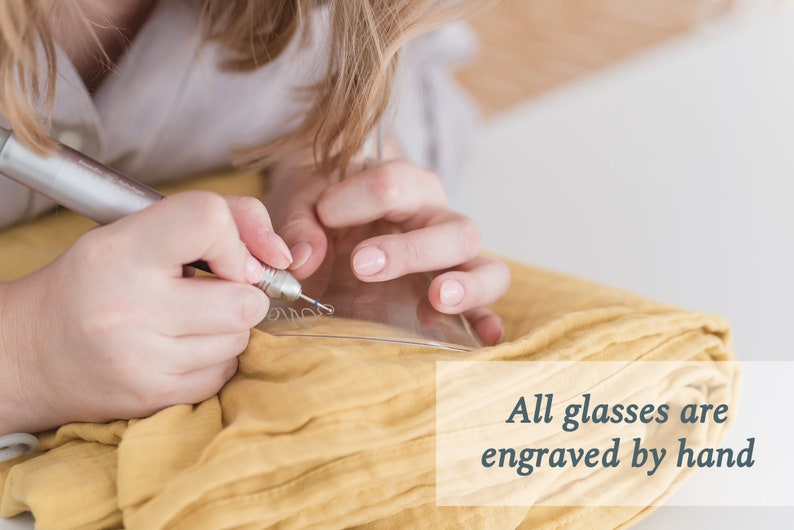 May include: A person is hand-engraving a glass with a small tool. The text "All glasses are engraved by hand" is visible in the image.