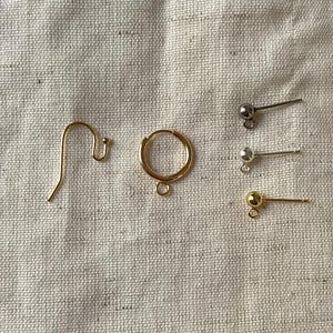 May include: A set of gold earring findings, including a hoop, a hook, and three pairs of post earrings with gold and silver balls.