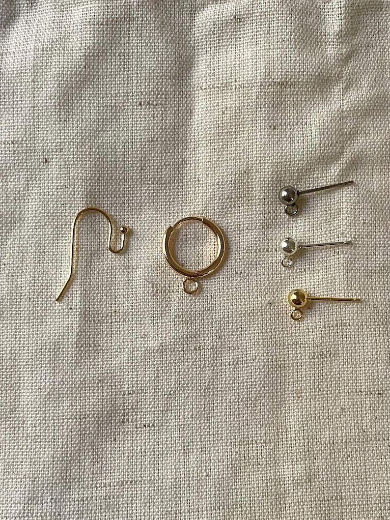 May include: A set of gold earring findings, including a hoop, a hook, and three pairs of post earrings with gold and silver balls.