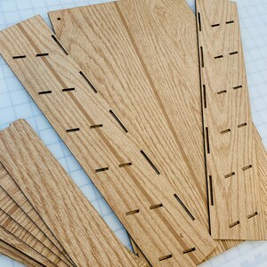 May include: A set of wooden craft pieces with slots cut out. The pieces are various sizes and shapes, and have a wood grain pattern.
