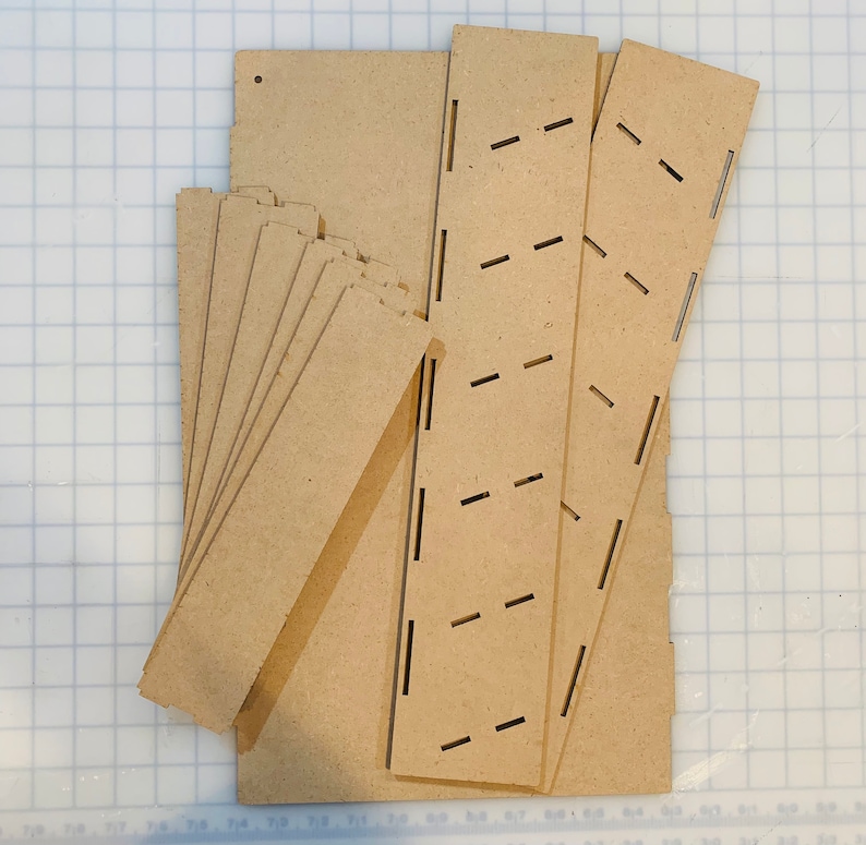 May include: A set of unfinished wooden pieces for building a shelf unit. The pieces are cut and ready to be assembled.