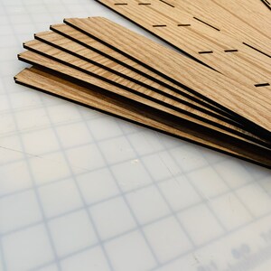 May include: A set of seven wooden pieces with a wood grain pattern and black edges. The pieces are stacked on top of each other and are arranged in a fan shape.