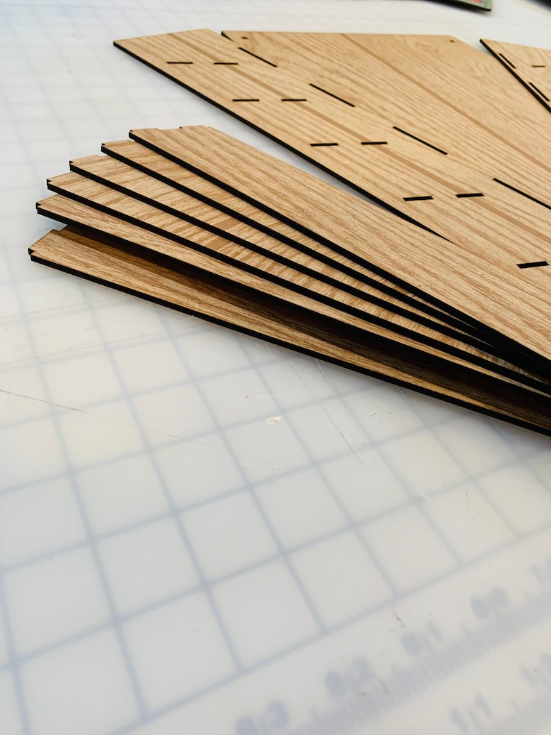 May include: A set of seven wooden pieces with a wood grain pattern and black edges. The pieces are stacked on top of each other and are arranged in a fan shape.