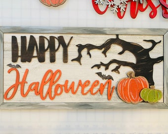 May include: A wooden sign with a distressed white background and a gray frame. The sign says "Happy Halloween" in black and orange letters. There is a black silhouette of a tree with branches and bats. There are also two pumpkins, one orange and one green.