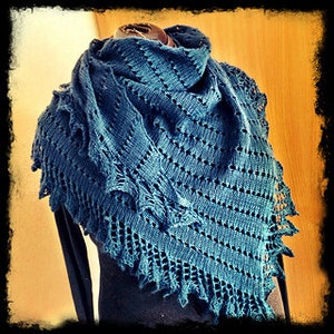 May include: A teal blue knitted shawl with a lacy pattern. The shawl is draped over a mannequin.
