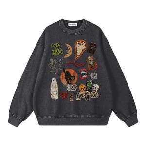 Puede incluir: Una sudadera de cuello redondo en color gris carbón con un collage de gráficos temáticos de Halloween que incluyen un gato negro, fantasmas, esqueletos, calabazas, una luna y los textos Love at First Fright, Spook Show y Are We Weird?.