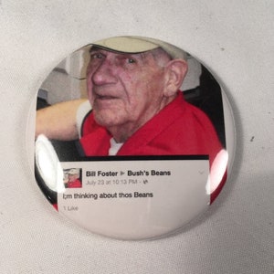 May include: A white button with a red, white, and blue image of a man wearing a red shirt and a beige hat. The image is a screenshot of a Facebook post that reads "Bill Foster Bush's Beans July 23 at 10:13 PM I'm thinking about thos Beans 1 Like."