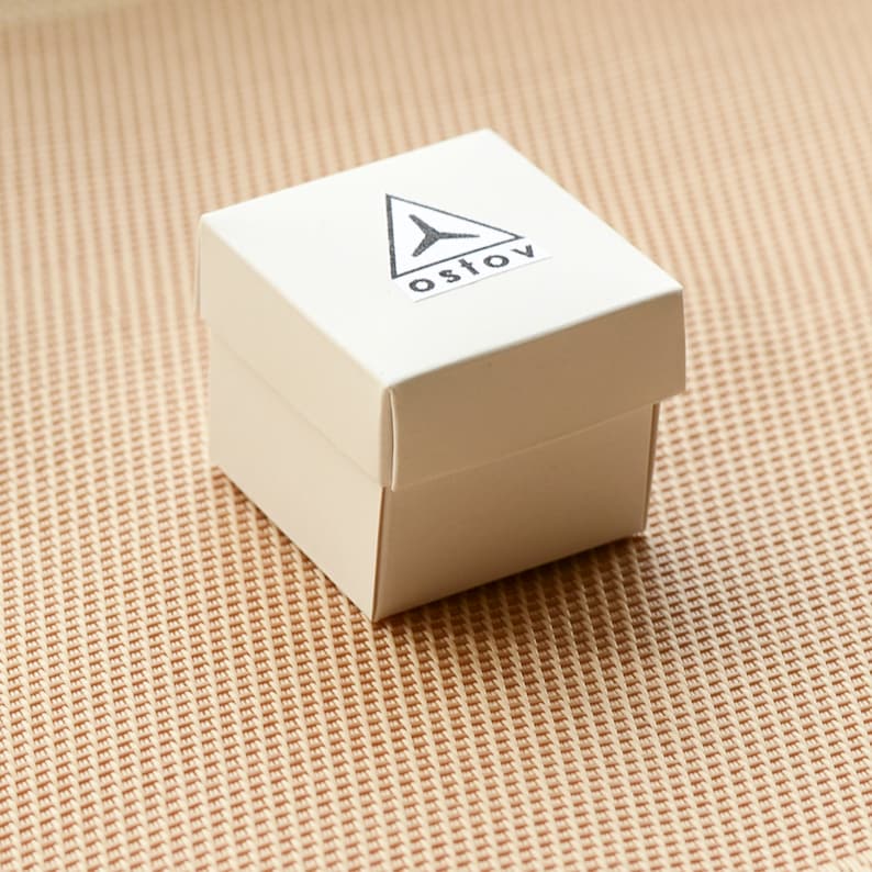 May include: A white square box with a black triangle logo and the word "OSTOV" printed on it.