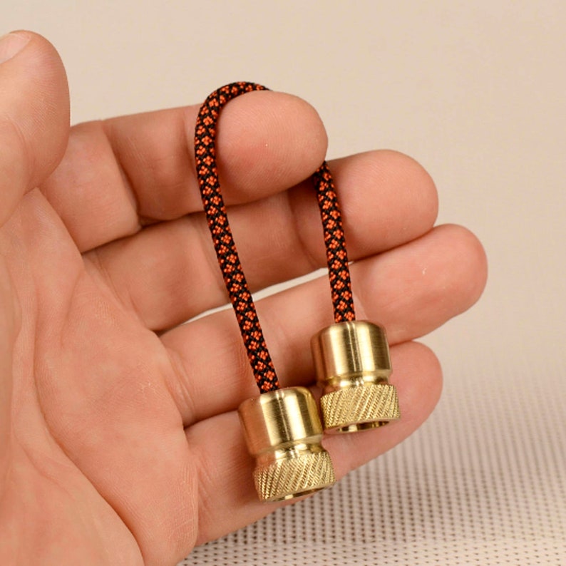 May include: A pair of brass fidget toys with black and orange braided cord.
