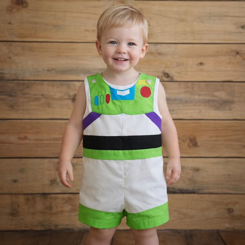 Puede incluir: Un pelele con el tema de Buzz Lightyear, con un dise&ntilde;o verde y blanco. El atuendo sin mangas presenta un panel de pecho verde con botones y detalles coloridos, una franja negra en la secci&oacute;n media y ribete verde en los pantalones cortos. El pelele es para un ni&ntilde;o peque&ntilde;o.