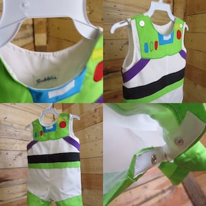 Puede incluir: Un disfraz de Buzz Lightyear para ni&ntilde;o, que presenta un mono verde y blanco con detalles morados y negros. El disfraz incluye un chaleco con detalles de botones y un cuello, exhibido en una percha blanca. El disfraz tiene la palabra "Bubbles" en el interior.