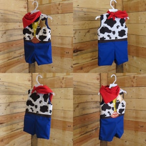 May include: A cowboy-themed costume set, including a vest with a cowhide pattern, blue shorts, and a red bandana. The vest features a brown belt design. The costume is displayed on a white hanger against a wooden background.