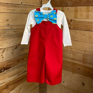 May include: Red overalls with a white long-sleeved shirt and a blue and yellow polka dot bow tie.