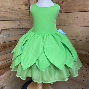 May include: A green tulle dress with a layered skirt and a sleeveless bodice. The dress is on a white dress form.