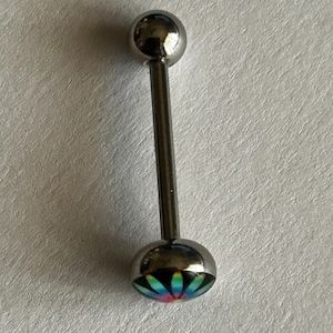 May include: A silver-toned barbell body jewelry piece featuring a smooth spherical top bead and a flat circular bottom end. The bottom end displays a vibrant, multi-colored radial flower pattern with shades of blue, green, yellow, and pink.