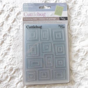 May include: A Cuttlebug embossing folder by Provo Craft in its original packaging. The clear plastic folder features a repeating pattern of nested rectangles. The packaging includes the text Traffic Jam, Cuttlebug, and Provo Craft.