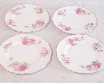May include: Set of four white ceramic plates with a pink floral design. The plates have a gold rim and are perfect for a tea party or special occasion.