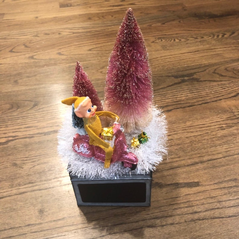 Vintage Pixie Elf knee hugger rides a pink scooter on kistch tabletop decor