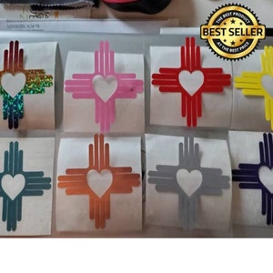 Pode incluir: Conjunto de dez adesivos de vinil com o s&iacute;mbolo do estado do Novo M&eacute;xico, um s&iacute;mbolo estilizado do sol Zia com um cora&ccedil;&atilde;o no centro. Os adesivos est&atilde;o dispon&iacute;veis em uma variedade de cores, incluindo vermelho, rosa, azul, verde, amarelo, laranja e cinza.