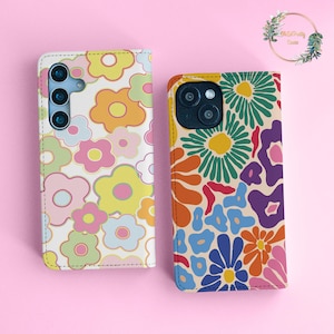 Puede incluir: Dos fundas para teléfono con un diseño floral retro. La funda de la izquierda tiene un fondo blanco con flores rosas, amarillas y azules. La funda de la derecha tiene un fondo beige con flores verdes, naranjas, rojas y azules.
