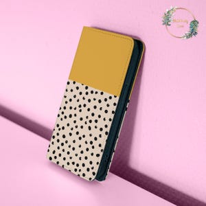 May include: A yellow and white phone case with a black polka dot pattern. The case is made of a soft, durable material and is designed to protect your phone from scratches and bumps.