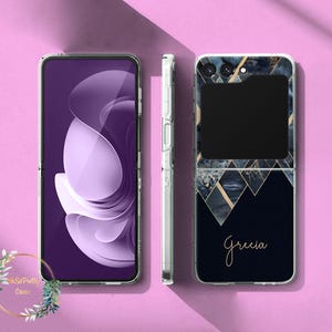 Puede incluir: Una funda transparente para teléfono con un diseño abstracto púrpura en la pantalla. La funda del teléfono de la derecha tiene un diseño geométrico azul marino y dorado con el nombre "Grecia" en escritura dorada. El teléfono está abierto y cerrado.