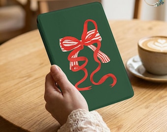 May include: A dark green e-reader case featuring a central graphic of a red and white striped ribbon tied into a bow with long, flowing tails. The cover has a smooth, matte finish and displays a festive, holiday-inspired design on the front.