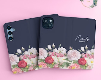Könnte beinhalten: Zwei dunkelblaue Handyhüllen mit einem Blumendesign. Die Hülle rechts hat den Namen "Emily Lindsey" aufgedruckt.