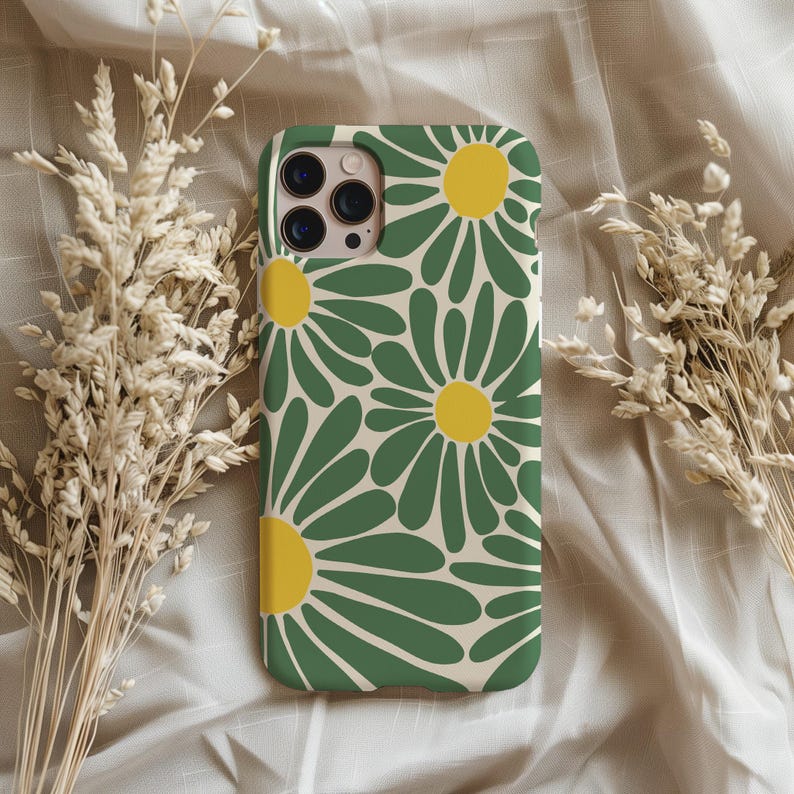 May include: A phone case with a daisy pattern. The case features a cream-colored background with large green daisy petals and yellow centers. The case is designed to fit a smartphone and has cutouts for the camera and buttons.