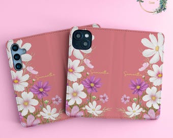 Könnte beinhalten: Eine rosa Handyhülle mit Blumenmuster. Die Hülle hat ein Muster aus weißen und lila Blumen mit dem Namen "Samantha" darauf.