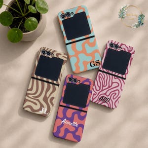 May include: Four foldable smartphone cases with distinct patterns and personalised lettering. One case features orange and light blue waves with GS, one has beige and brown swirls with JL, one has pink and red brain-like patterns with AKR, and one has purple and orange waves with Annette.