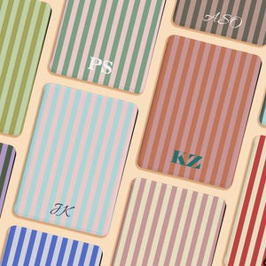 May include: A collection of rectangular luggage tags featuring vertical stripes in various color combinations including olive, pink, teal, terracotta, purple, and red. Each tag is personalized with different two or three-letter monograms.