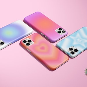 May include: Four different phone cases with gradient designs. The cases are in shades of blue, pink, orange, and yellow. The cases are all for the same model phone and have a similar design aesthetic.