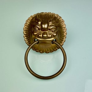 May include: A gold lion's head door knocker with a ring handle.
