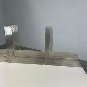 Pu&ograve; includere: Un set di ferma libri in plastica trasparente, impilati e disposti a scalare. I ferma libri sono progettati per tenere i libri in posizione verticale su uno scaffale o una scrivania.