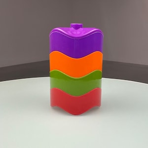 Puede incluir: Un juguete apilable con cuatro secciones en morado, naranja, verde y rojo. Cada sección tiene un diseño ondulado.
