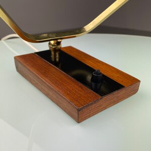 May include: A brass and wood table lamp with a black switch. The lamp has a geometric design and a wooden base.