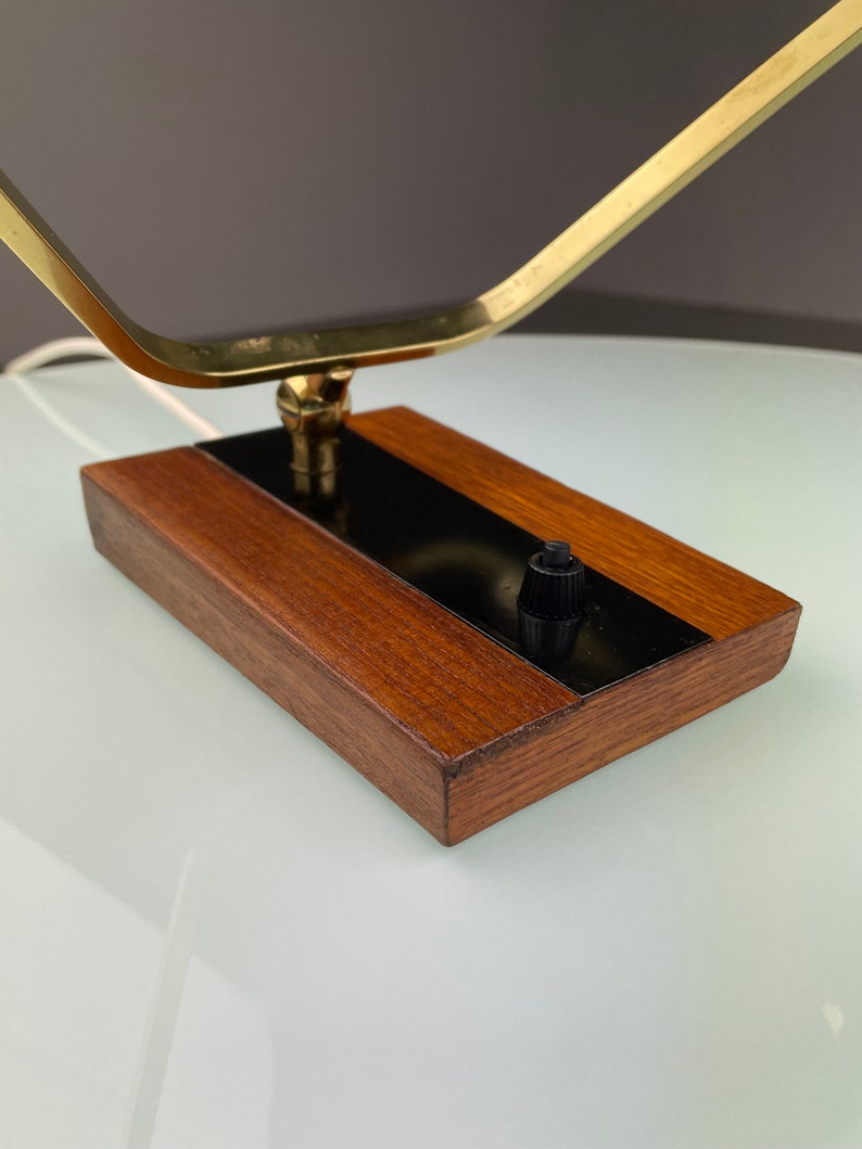 May include: A brass and wood table lamp with a black switch. The lamp has a geometric design and a wooden base.