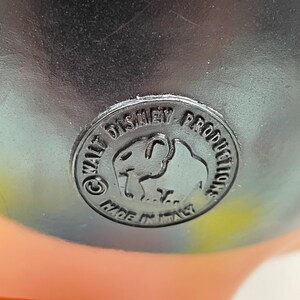 May include: Close-up of a black plastic label with the text "Walt Disney Productions" and a cartoon elephant logo. The label also says "Made in Italy".