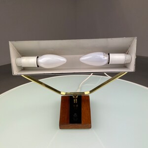 May include: A brass and wood desk lamp with a white shade and two light bulbs. The lamp has a simple, modern design.