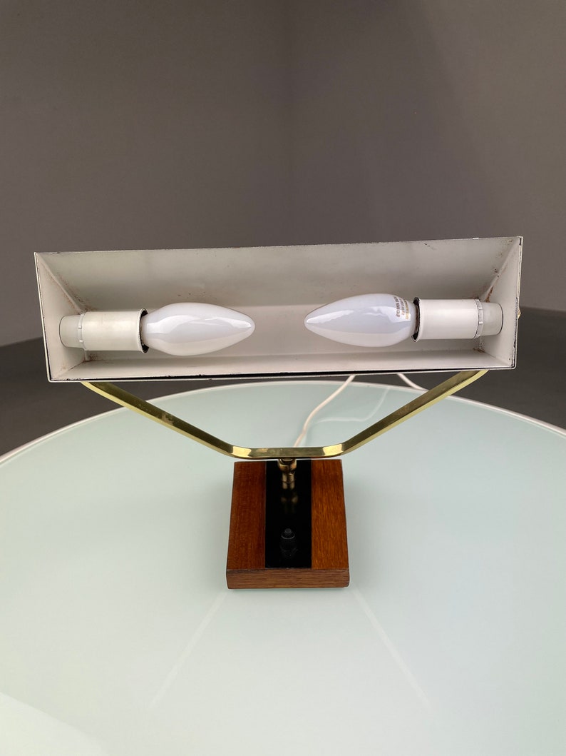 May include: A brass and wood desk lamp with a white shade and two light bulbs. The lamp has a simple, modern design.