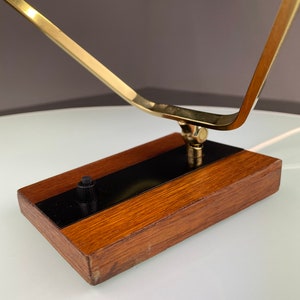 May include: A brass and wood table lamp with a geometric design. The lamp has a black switch on the wooden base.