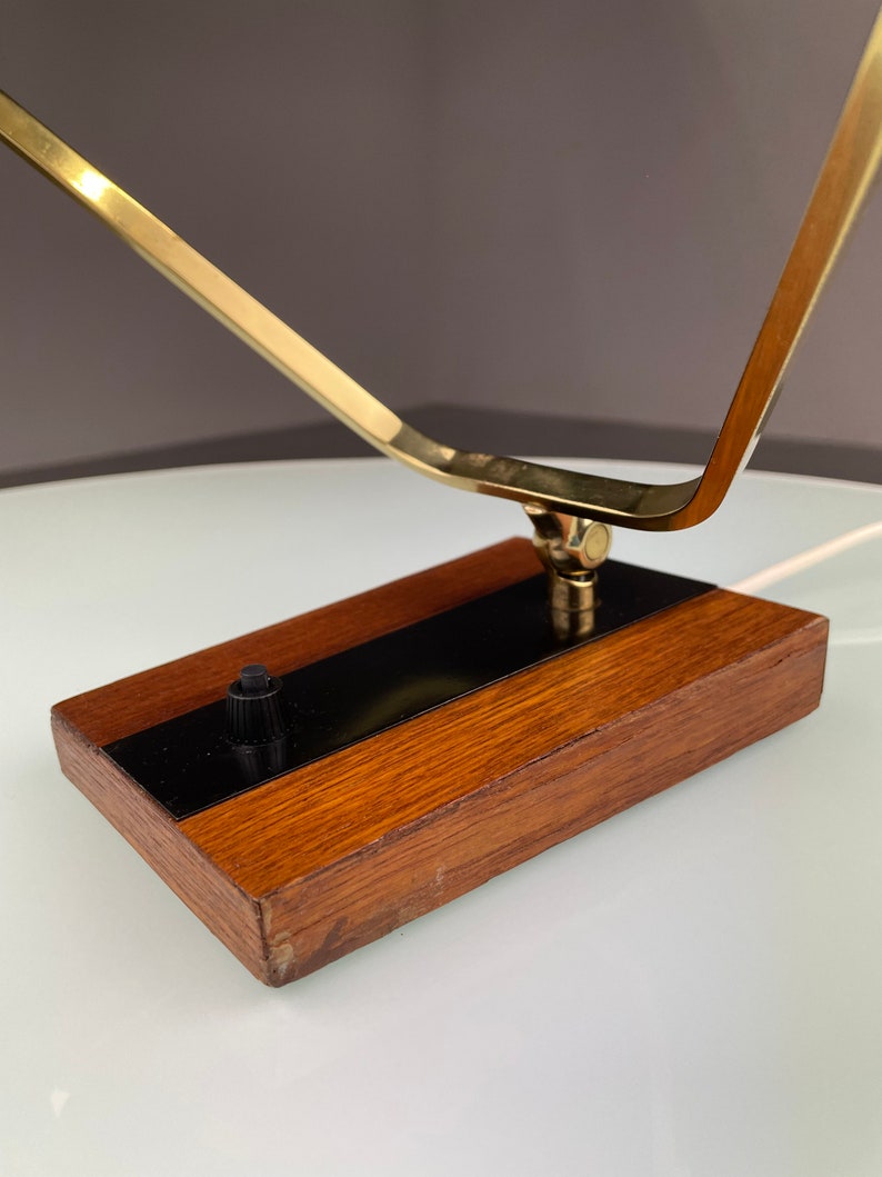 May include: A brass and wood table lamp with a geometric design. The lamp has a black switch on the wooden base.