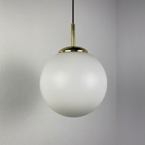 Op de afbeelding: Een witte bolvormige hanglamp met een messing afwerking. De lamp hangt aan een zwart snoer.